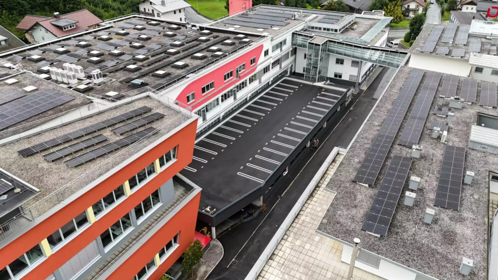 01_eurofunk Luftaufnahme eines modernen Bürogebäudes mit roten Fassaden und zahlreichen Solarpaneelen auf den Dächern im Bereich