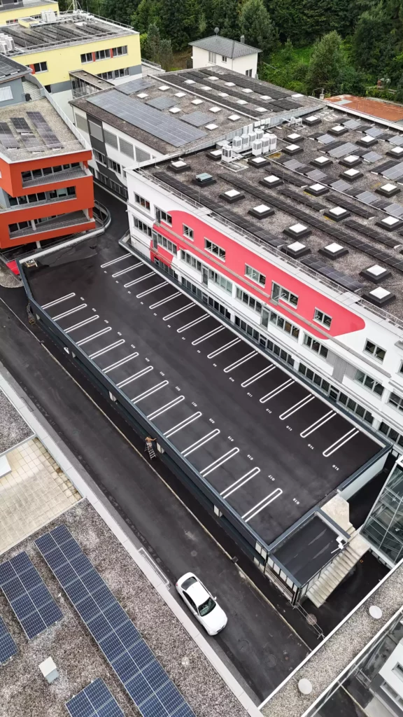 default Luftaufnahme eines modernen Bürogebäudes mit Parkdeck, Solarpaneelen auf den Dächern und einem weißen Auto auf der Straße