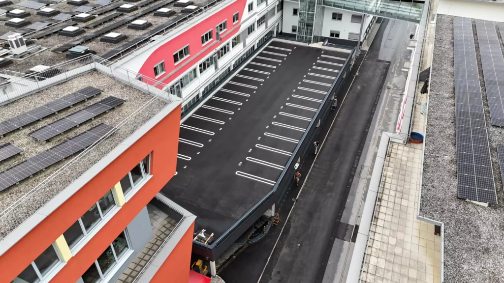 04_eurofunk Dachansicht eines modernen Bürogebäudes mit Solarpaneelen und leerem Parkdeck, umgeben von Straßen und Gebäuden