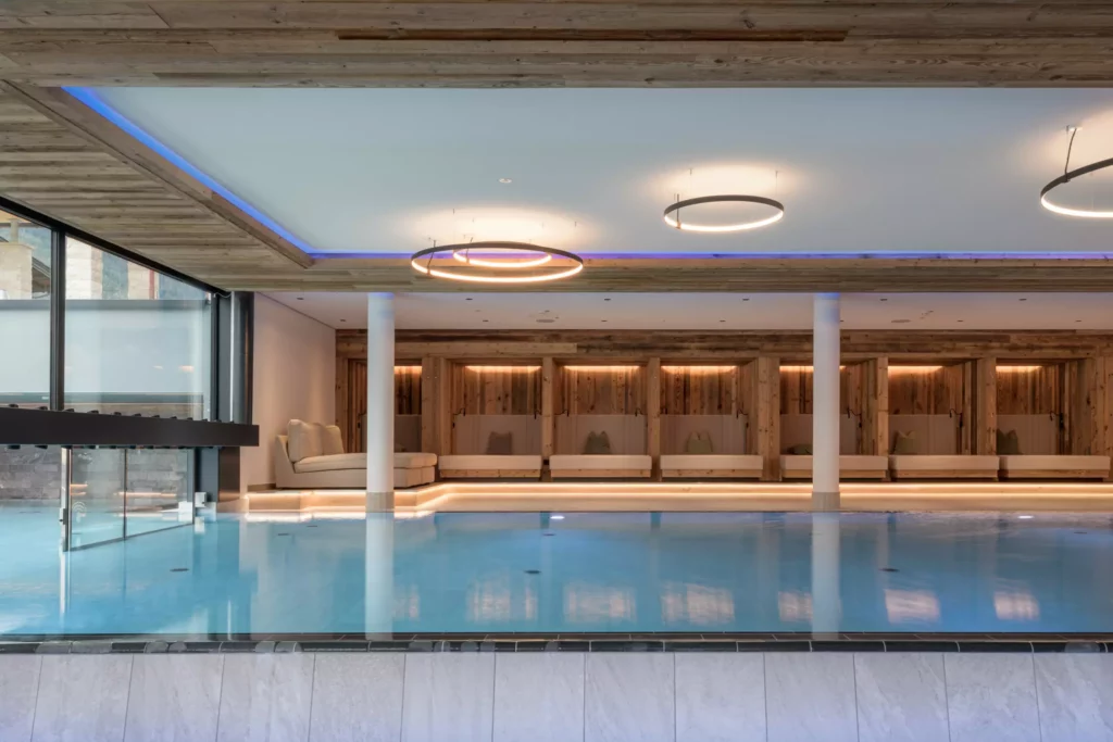 2024-06-13_Deutinger-Hotel-Kesselgrub-©sobietzki-high-res-3 Moderner Innenpool mit Holzdecke, runden Deckenleuchten und gemütlichen Sitznischen im Hotel Kesselgrub
