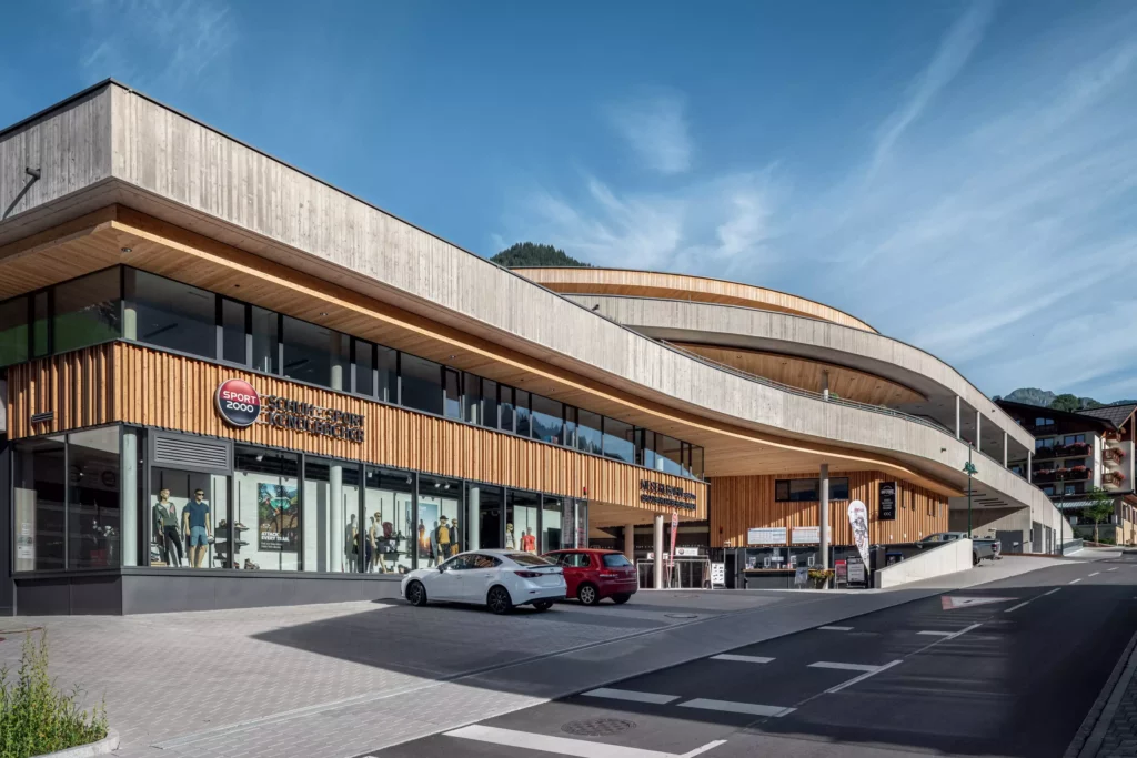 2024-08-19_Talstation-Kieserl-Grossarl-©sobietzki-low-res-2560px-1 Moderne Talstation Kieserl in Großarl mit Holzfassade, großen Schaufenstern und Parkplätzen bei klarem Himmel und Bergkulisse