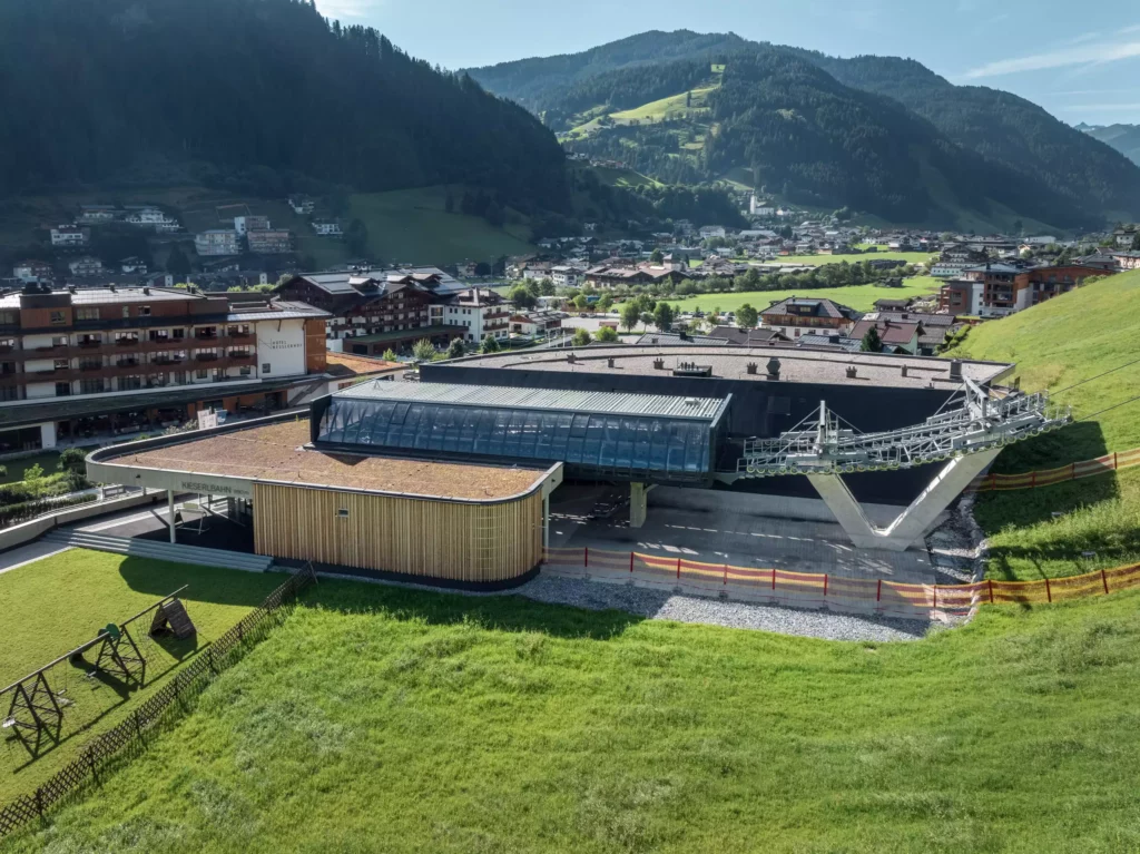 2024-08-19_Talstation-Kieserl-Grossarl-©sobietzki-low-res-2560px-18 Moderne Talstation der Kieserlbahn in Großarl mit umliegenden Gebäuden und grünen Bergen im Hintergrund bei Sonnenschein
