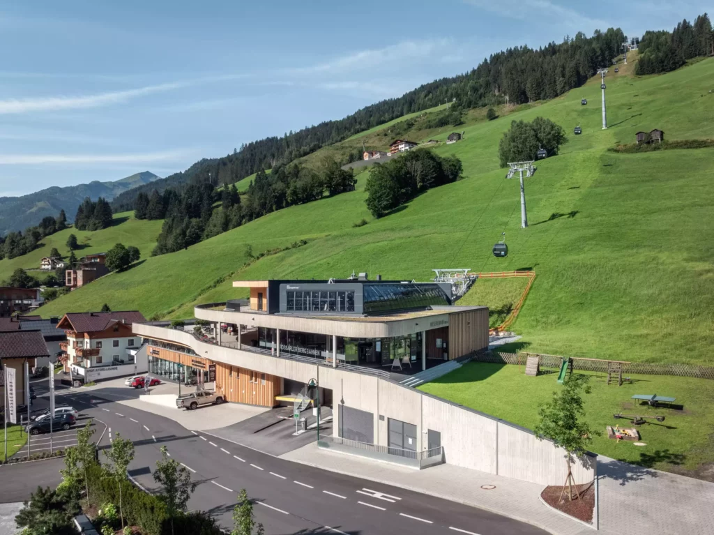 2024-08-19_Talstation-Kieserl-Grossarl-©sobietzki-low-res-2560px-9 Moderne Talstation Kieserl in Großarl mit Seilbahn, umgeben von grünen Hügeln und Bergen, Parkplätzen und Spielplatz.