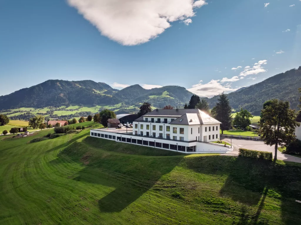 251016_Deutinger-Mitarbeiterhaus-Pichlarn-©sobietzki-low-res-2560px-20 Modernes Mitarbeiterhaus auf grünem Hügel mit Bergen im Hintergrund bei klarem Himmel in Pichlarn