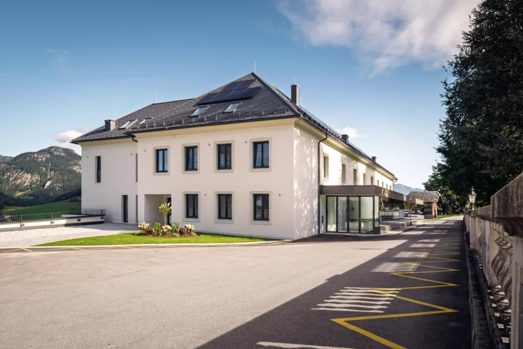 251016_Deutinger-Mitarbeiterhaus-Pichlarn-©sobietzki-low-res-2560px-4 Modernes zweistöckiges Mitarbeiterhaus mit Solarpaneelen auf dem Dach, umgeben von Bergen und Parkplätzen in Pichlarn