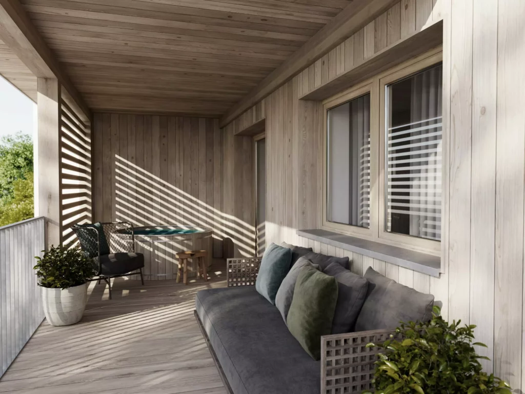 AppartementsNo37_3 Überdachter Balkon mit Holzverkleidung, grauem Sofa, Stuhl, kleinem Tisch und Pflanzen, Sonnenlicht fällt durch Lamellen.