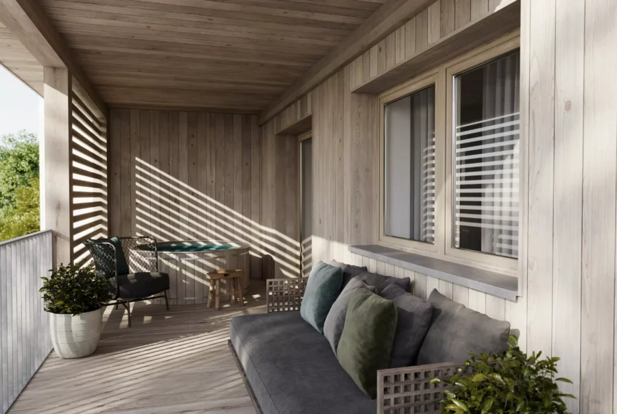 Überdachter Balkon mit Holzverkleidung, grauem Sofa, Stuhl, kleinem Tisch und Pflanzen, Sonnenlicht fällt durch Lamellen.