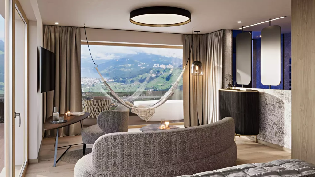 Hotel Berghof_07 Modern eingerichtetes Hotelzimmer mit Sitzbereich, Hängematte und Panoramafenster mit Bergblick im Hotel Berghof