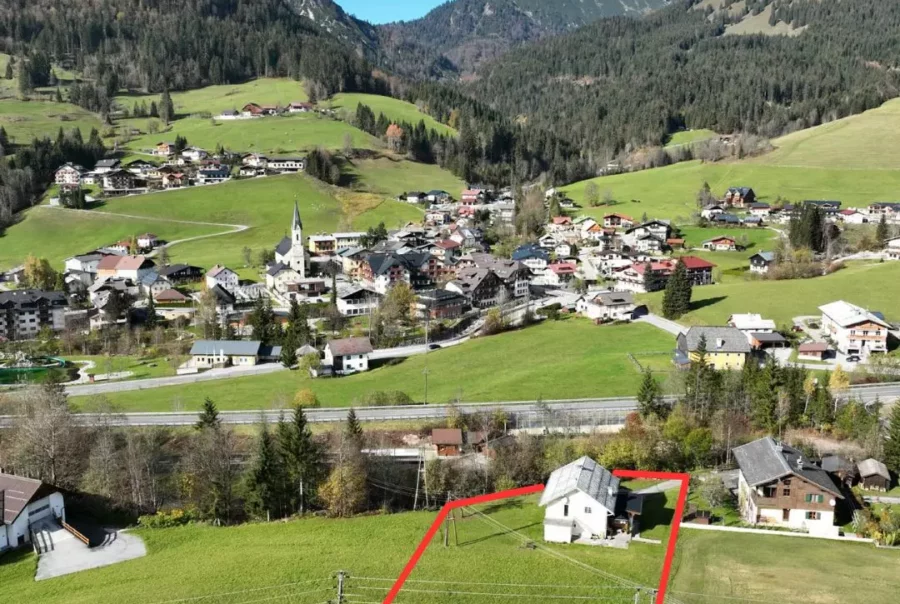 Luftaufnahme eines Hauses mit roter Grundstücksmarkierung in grüner Berglandschaft nahe Dorf Russbach mit Bergen im