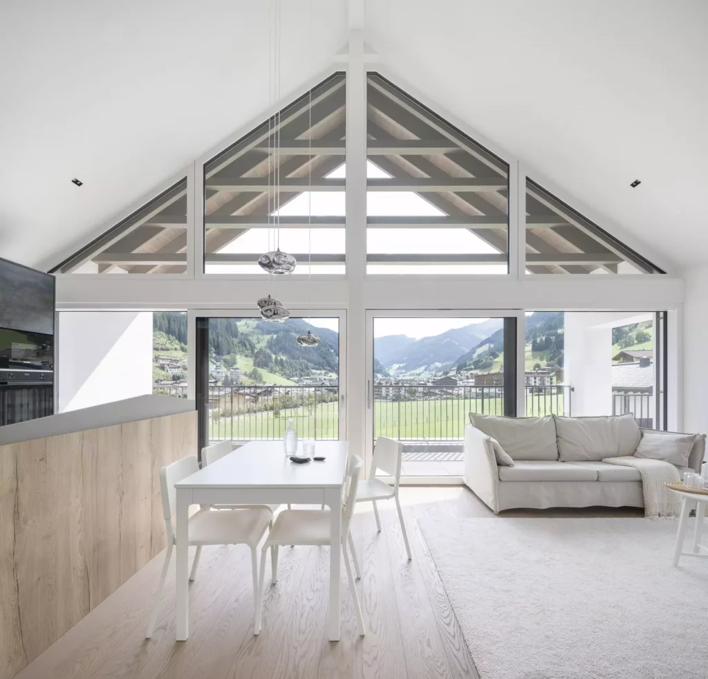 WB_Hofmann Helles modernes Wohnzimmer mit Essbereich, großen Panoramafenstern und Blick auf grüne Berge in Großarl, Hofmann