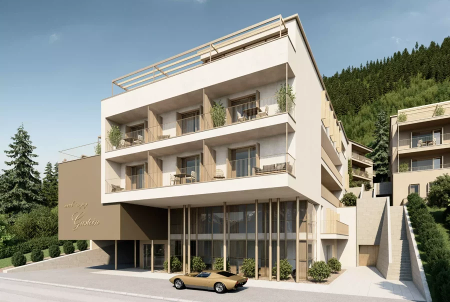 Moderner Wohnpark Gastein mit Balkonen, Terrasse, Eingangsbereich und einem Oldtimer-Pkw vor dem Gebäude am Hang mit Wald im