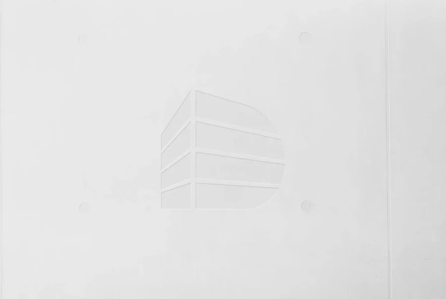 Weißer Betonwand mit eingraviertem stilisiertem Gebäude-Logo, minimalistisch und modern gestaltet, deutinger platzhalter