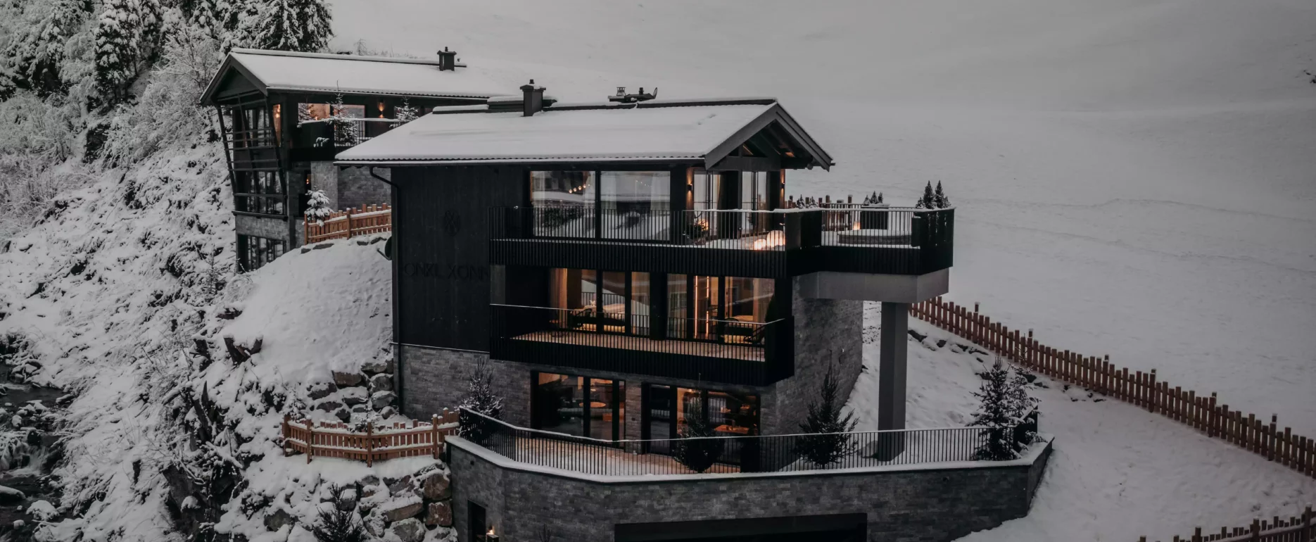 Modernes Wohnhaus mit großer Terrasse und Garage in verschneiter Berglandschaft bei Dämmerung in Großarl, Salzburg