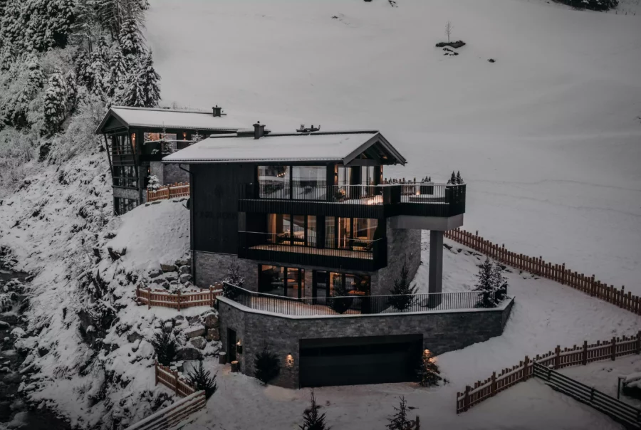 Modernes Wohnhaus mit großer Terrasse und Garage in verschneiter Berglandschaft bei Dämmerung in Großarl, Salzburg