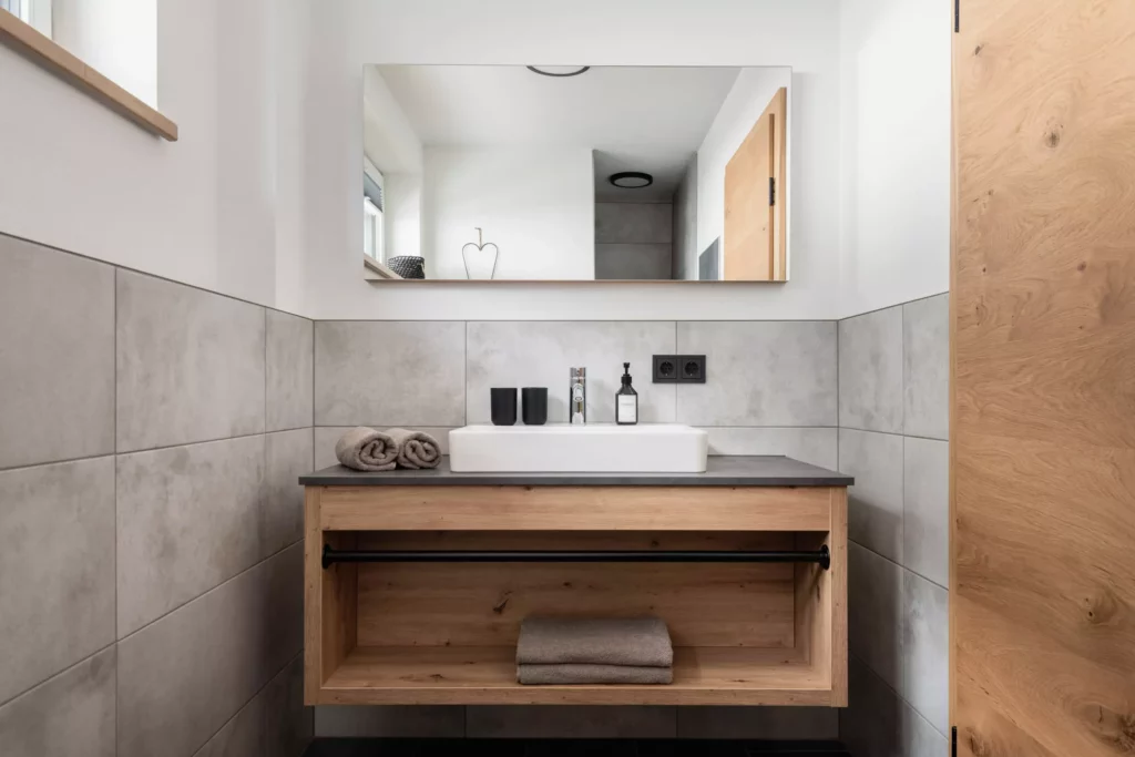 deutinger projektentwicklung baumanagement generalunternehmen immobilien grossarl hallein salzburg Hettegger-Sandra-©sobietzki-high-res-14 Modernes Badezimmer mit Holzwaschtisch, weißem Aufsatzbecken, grauen Handtüchern und großem Wandspiegel