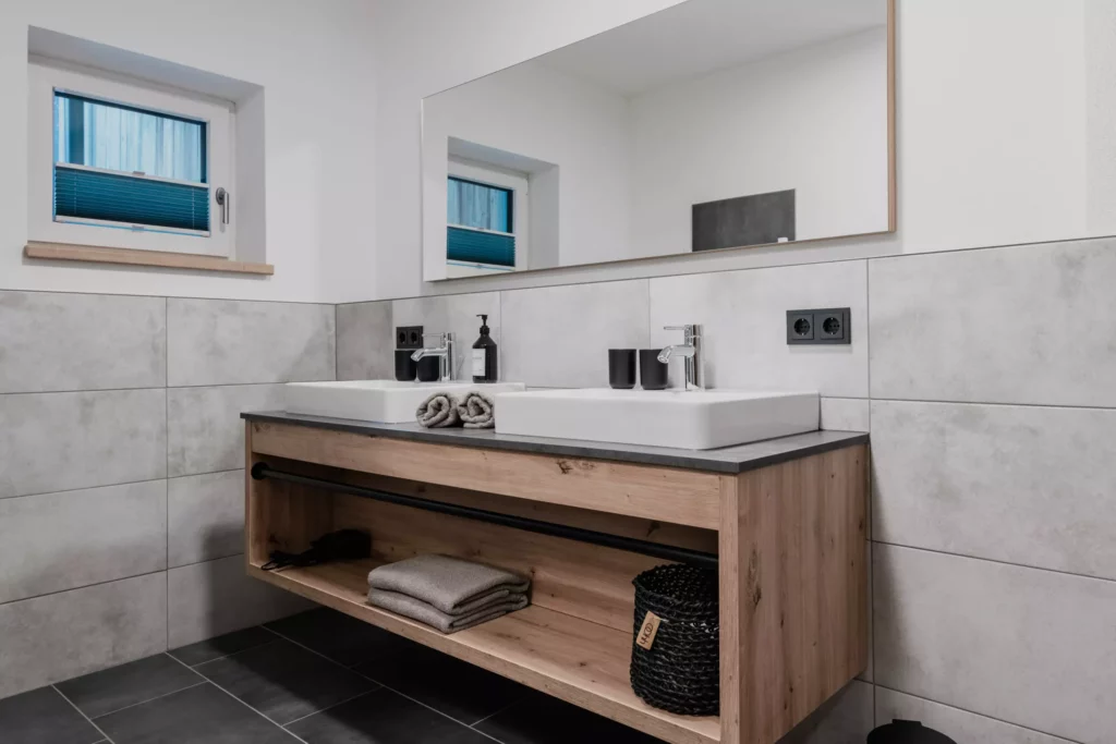 deutinger projektentwicklung baumanagement generalunternehmen immobilien grossarl hallein salzburg Hettegger-Sandra-©sobietzki-high-res-15 Modernes Badezimmer mit Doppelwaschbecken, großem Spiegel, Holzunterschrank und grauen Fliesen an Wand und Boden