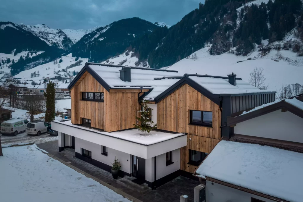 deutinger projektentwicklung baumanagement generalunternehmen immobilien grossarl hallein salzburg Hettegger-Sandra-©sobietzki-high-res-4 Modernes Wohnhaus mit Holzfassade und Schneebedecktem Flachdach vor verschneiter Berglandschaft in Großarl, Salzburg