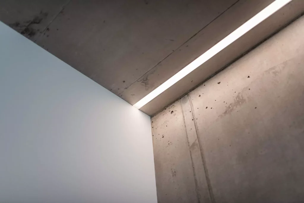 deutinger-projektentwicklung-baumanagement-generalunternehmen-immobilien-salzburg-Betriebshalle-Meister-Hallwang-19 Innenraum mit Betonwänden und Decke, moderner Lichtstreifen an der Decken-Ecke, minimalistische Bauplanung sichtbar