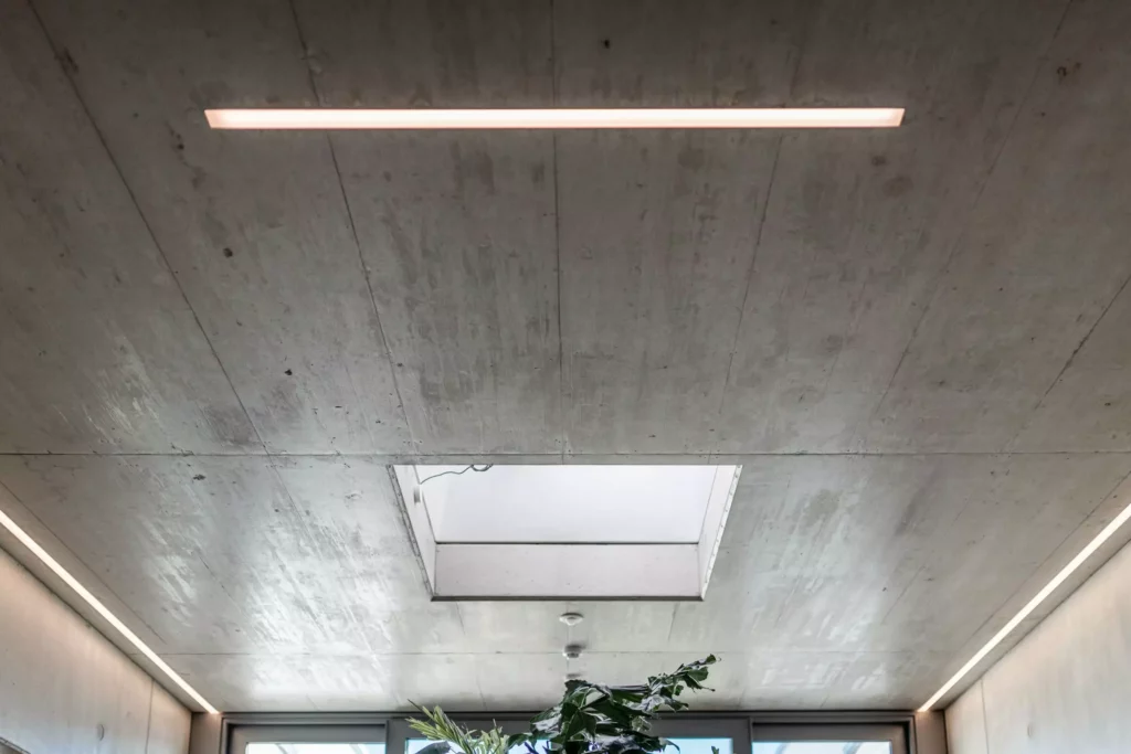 deutinger-projektentwicklung-baumanagement-generalunternehmen-immobilien-salzburg-Betriebshalle-Meister-Hallwang-21 Moderner Betonraum mit rechteckigem Oberlicht und integrierter LED-Beleuchtung an der Decke der Betriebshalle Meister