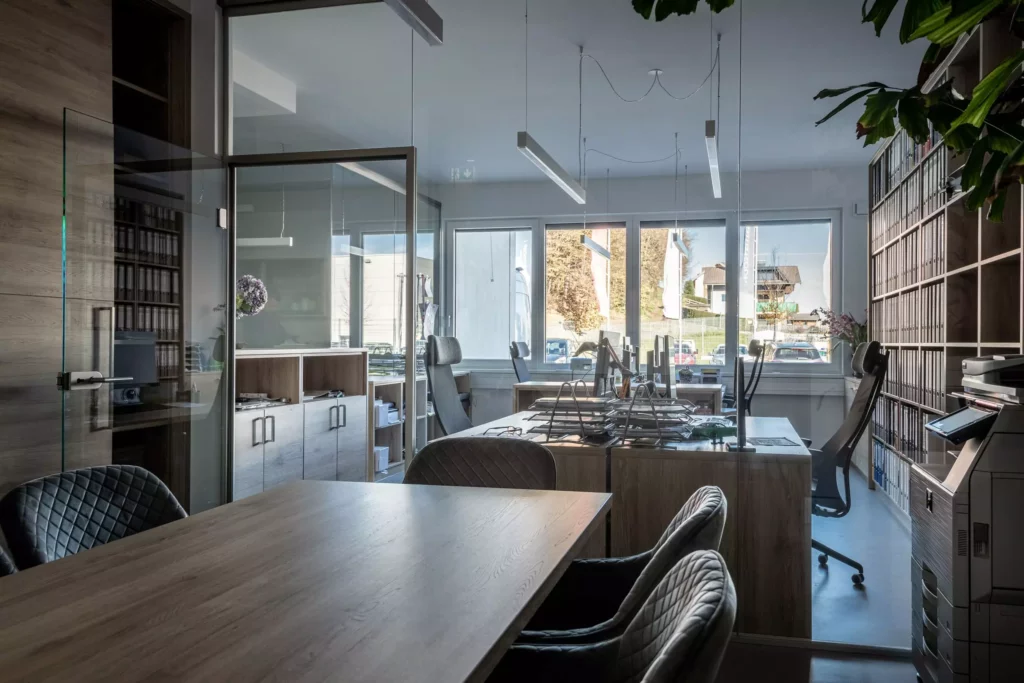 deutinger-projektentwicklung-baumanagement-generalunternehmen-immobilien-salzburg-Betriebshalle-Meister-Hallwang-24 Modernes Büro mit Holztischen, ergonomischen Stühlen, Aktenregalen und großen Fenstern mit Blick ins Freie in Salzburg