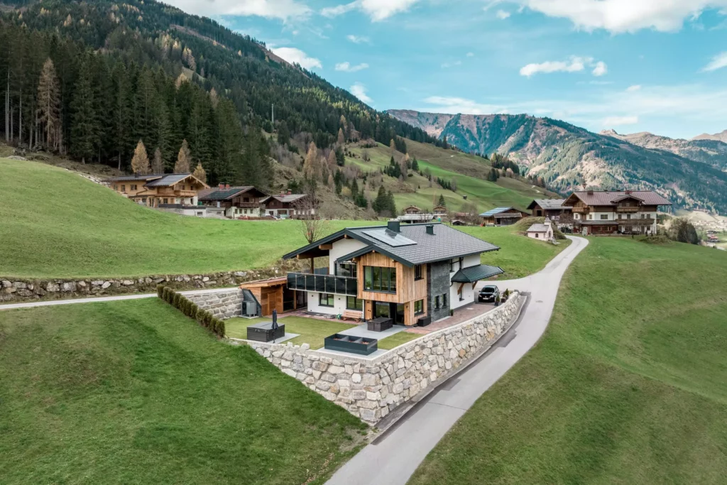 deutinger-projektentwicklung-baumanagement-generalunternehmen-immobilien-salzburg-MFH-Grossarl-Gfrerer-Schwarb-4 Modernes Mehrfamilienhaus mit Terrasse und Garten auf erhöhtem Grundstück in Großarl, umgeben von Bergen und Wiesen