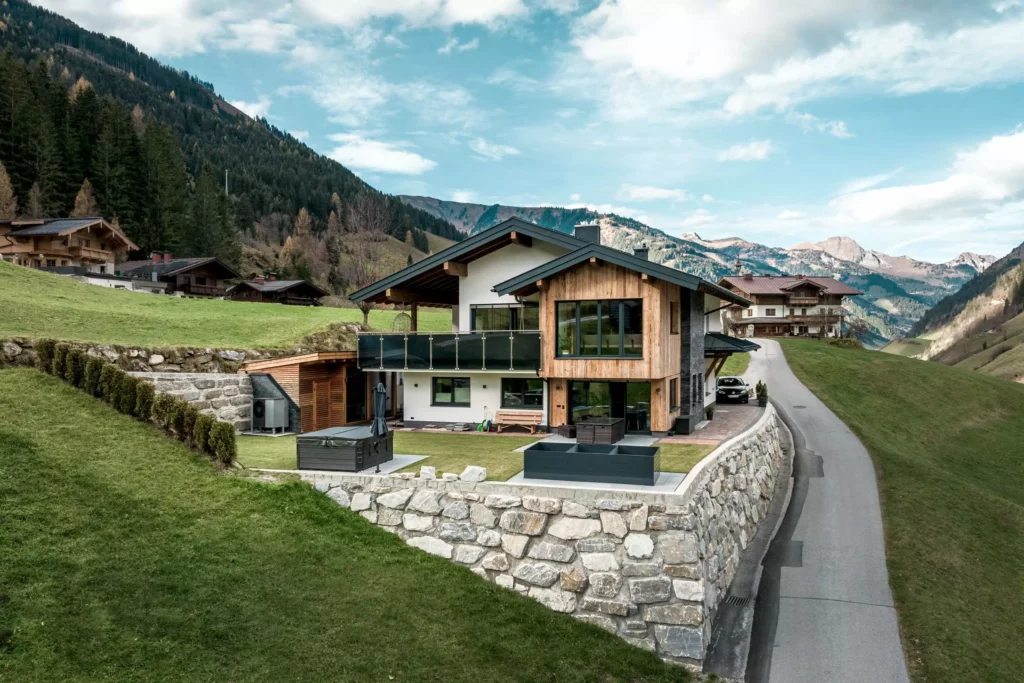 deutinger-projektentwicklung-baumanagement-generalunternehmen-immobilien-salzburg-MFH-Grossarl-Gfrerer-Schwarb-8 Modernes Mehrfamilienhaus mit Holzfassade und großer Terrasse in den Bergen von Großarl, Salzburg, umgeben von Wiesen und