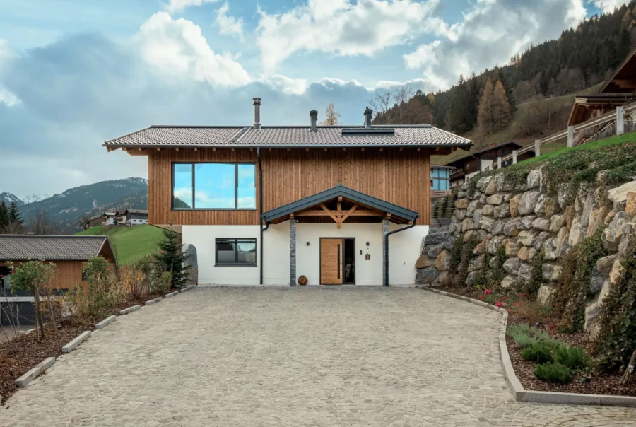 Modernes Mehrfamilienhaus mit Holzfassade und großer Einfahrt in bergiger Landschaft bei Großarl in Salzburg