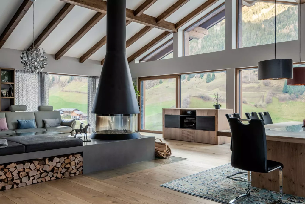 deutinger-projektentwicklung-baumanagement-generalunternehmen-immobilien-salzburg-MFH-Grossarl-Wagnermeyer-19 Modernes Wohnzimmer mit Kamin, Holzbalkendecke, großen Panoramafenstern und Bergblick in einem Mehrfamilienhaus in Großarl