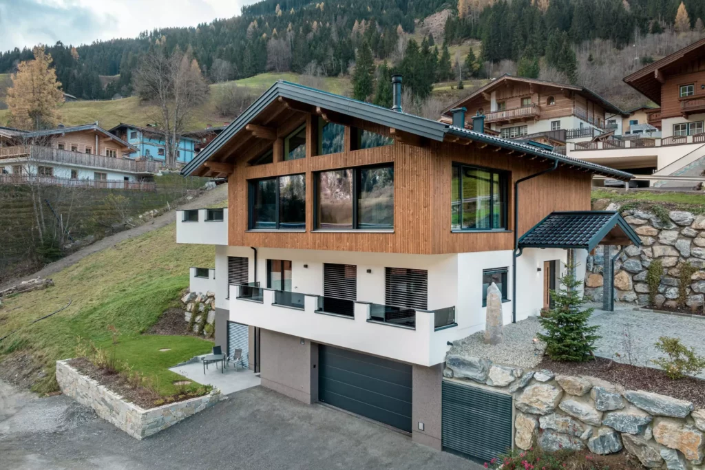 deutinger-projektentwicklung-baumanagement-generalunternehmen-immobilien-salzburg-MFH-Grossarl-Wagnermeyer-3 Modernes Mehrfamilienhaus mit Holzfassade und großen Fenstern in bergiger Landschaft in Großarl, Salzburg