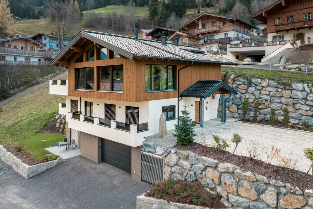 deutinger-projektentwicklung-baumanagement-generalunternehmen-immobilien-salzburg-MFH-Grossarl-Wagnermeyer-8 Modernes Mehrfamilienhaus mit Holzfassade und großen Fenstern in Hanglage, umgeben von Natur und weiteren Chalets in Großarl