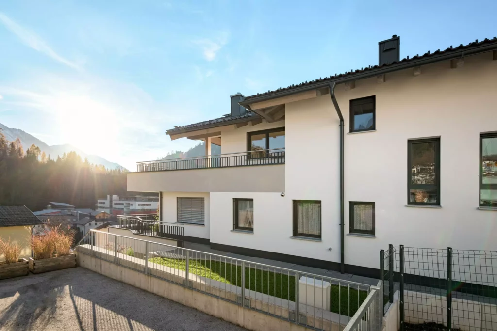 deutinger-projektentwicklung-baumanagement-generalunternehmen-immobilien-salzburg-Mehrfamilienhaus-Altenberger-4 Modernes Mehrfamilienhaus mit Balkonen und Bergpanorama bei Sonnenuntergang in Salzburg, Projektentwicklung und Baumanagement