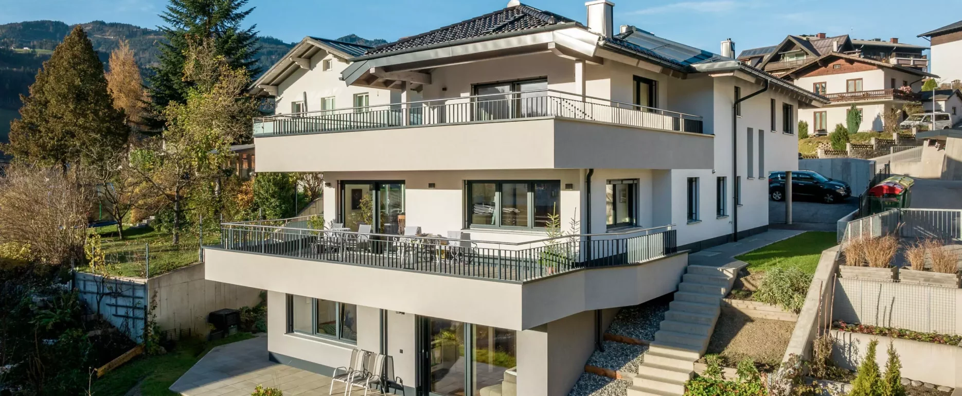 Modernes Mehrfamilienhaus mit großen Balkonen und Terrasse in sonniger Hanglage vor Bergkulisse in Salzburg