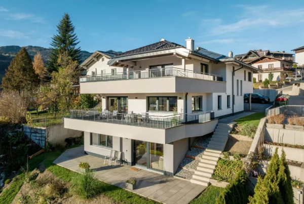Modernes Mehrfamilienhaus mit großen Balkonen und Terrasse in sonniger Hanglage vor Bergkulisse in Salzburg