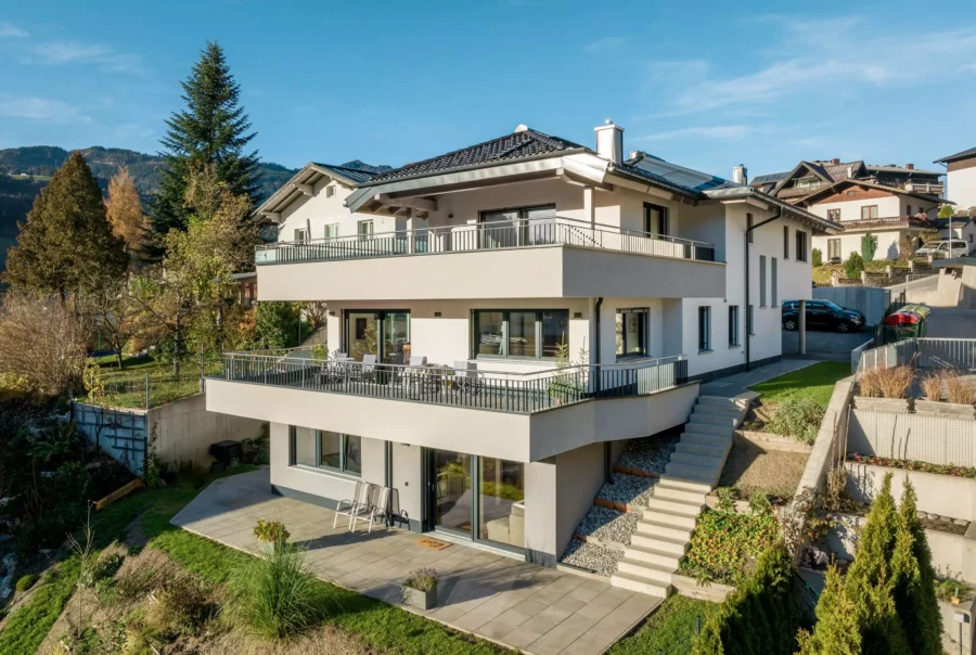 Modernes Mehrfamilienhaus mit großen Balkonen und Terrasse in sonniger Hanglage vor Bergkulisse in Salzburg
