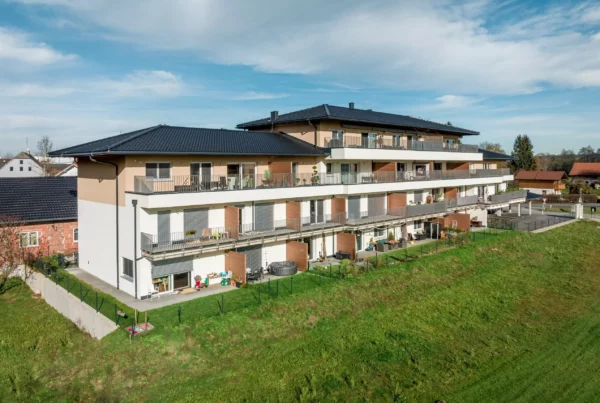 Modernes Wohngebäude mit Balkonen und Gartenflächen im Panoramapark Uttendorf bei Salzburg unter blauem Himmel