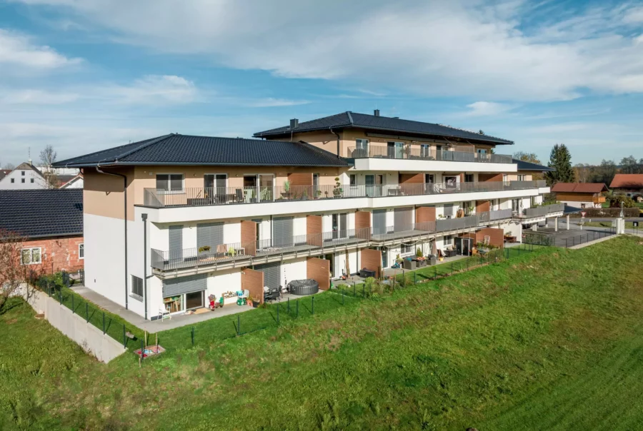 Modernes Wohngebäude mit Balkonen und Gartenflächen im Panoramapark Uttendorf bei Salzburg unter blauem Himmel