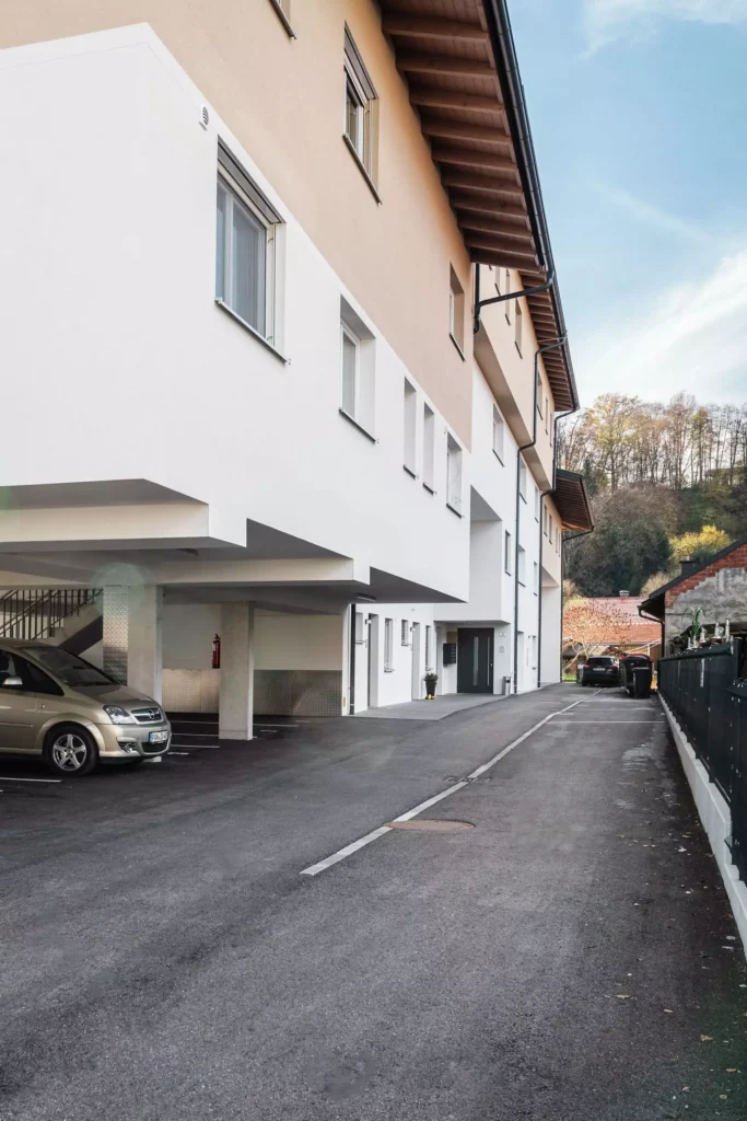 deutinger-projektentwicklung-baumanagement-generalunternehmen-immobilien-salzburg-Panoramapark-Uttendorf-4 Moderner Wohnkomplex mit Parkplätzen und Zufahrtsstraße im Panoramapark Uttendorf bei Salzburg, Bauprojektmanagement sichtbar