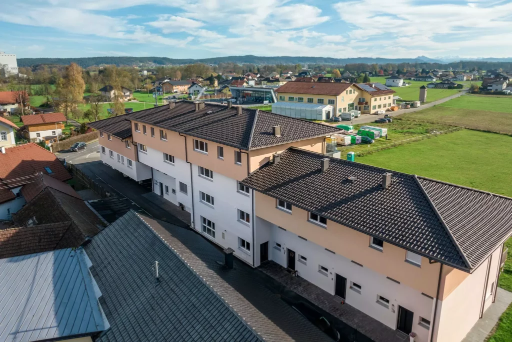 deutinger-projektentwicklung-baumanagement-generalunternehmen-immobilien-salzburg-Panoramapark-Uttendorf-9 Mehrfamilienhaus mit braunem Dach und weiß-beiger Fassade im ländlichen Panoramapark Uttendorf bei Salzburg
