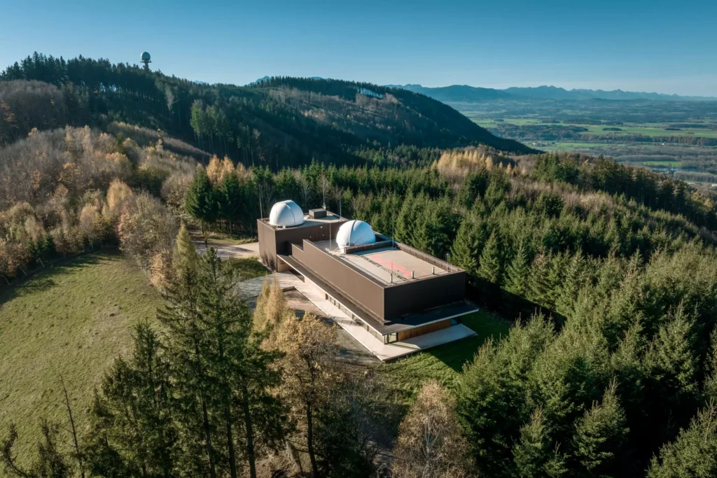 deutinger-projektentwicklung-baumanagement-generalunternehmen-immobilien-salzburg-Sternwarte-Haus-der-Natur-12 Modernes Bauprojekt mit zwei Kuppeln inmitten eines bewaldeten Gebirgsgebiets nahe Salzburg, klare Sicht ins Tal