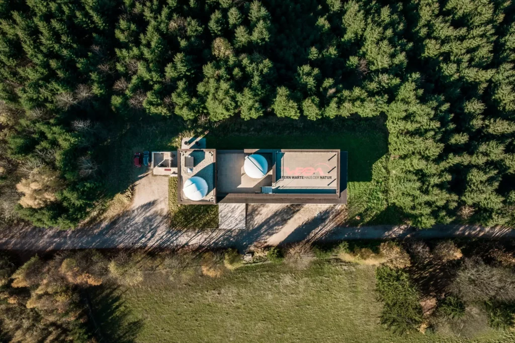 deutinger-projektentwicklung-baumanagement-generalunternehmen-immobilien-salzburg-Sternwarte-Haus-der-Natur-13 Luftaufnahme des Gebäudes Sternwarte Haus der Natur umgeben von Wald und Wiesen in Salzburg mit zwei Kuppeln auf dem Dach