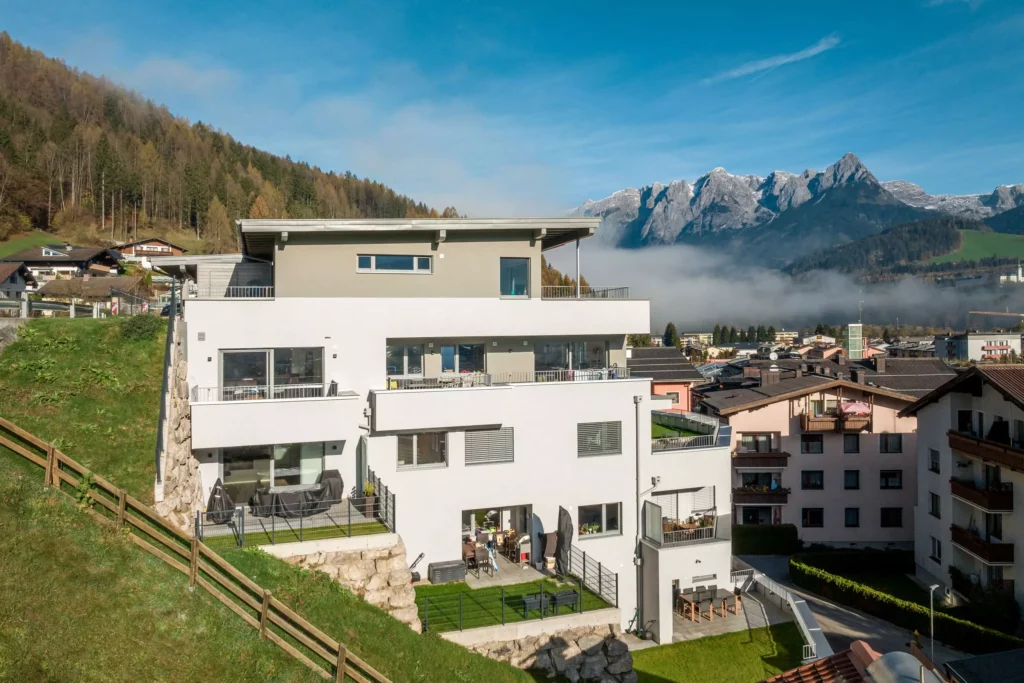 deutinger-projektentwicklung-baumanagement-generalunternehmen-immobilien-salzburg-Wohnpark-Bischofshofen-11 Moderner Wohnpark in Bischofshofen mit Bergpanorama und umliegenden Häusern im sonnigen Herbstlicht