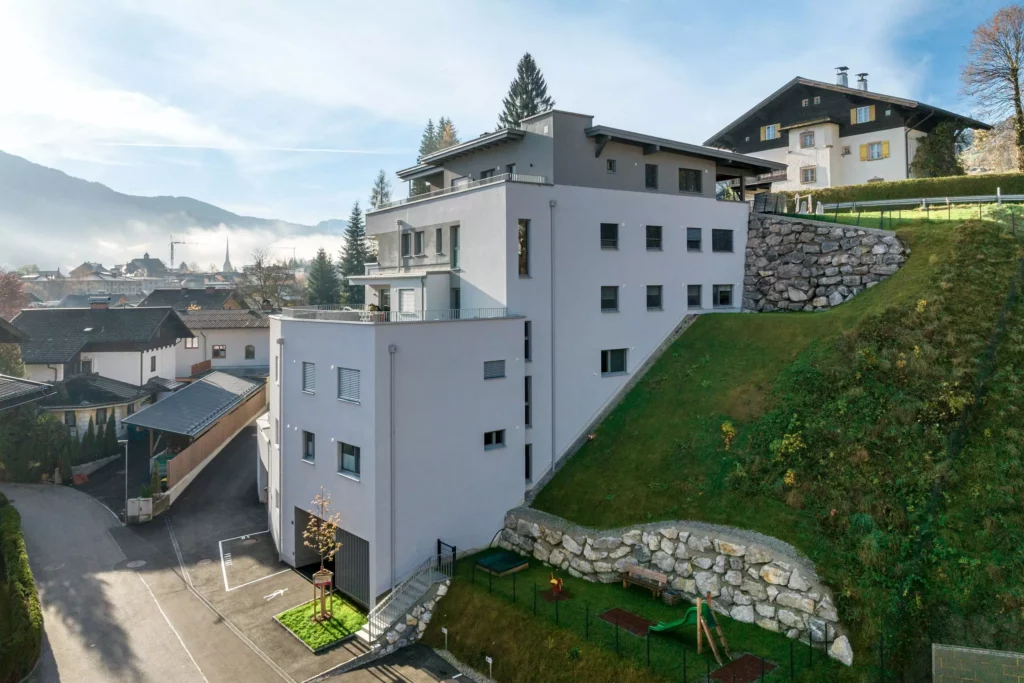 deutinger-projektentwicklung-baumanagement-generalunternehmen-immobilien-salzburg-Wohnpark-Bischofshofen-8 Moderner Wohnpark mit mehrstöckigem Gebäude am Hang und Bergpanorama in Bischofshofen, Salzburg