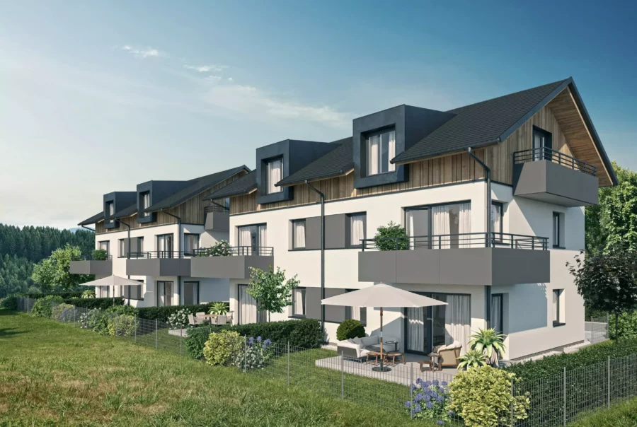 Moderne Reihenhäuser mit Balkonen und Terrassen, umgeben von Grünflächen und Bäumen, unter blauem Himmel bei Tageslicht.