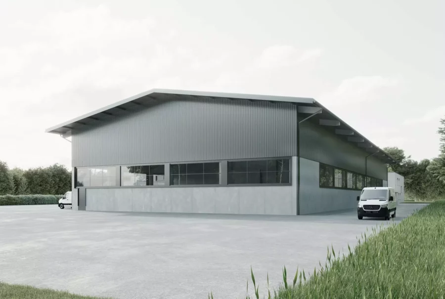 Moderne Betriebshalle mit grauer Fassade und großen Fenstern, davor zwei weiße Transporter, umgeben von Grünflächen und