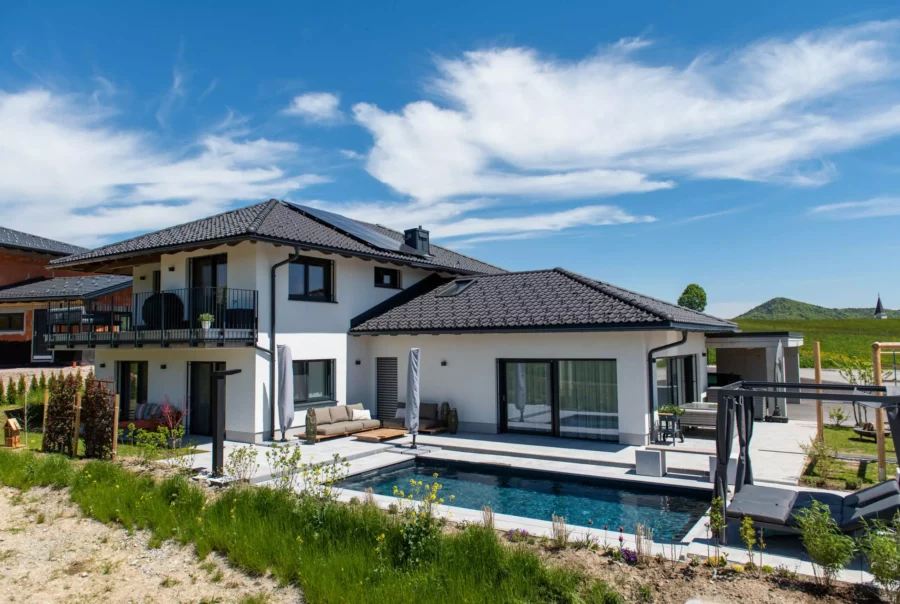 Modernes Einfamilienhaus mit Pool, Terrasse und Garten unter blauem Himmel, Beispiel für Bauprojektmanagement und