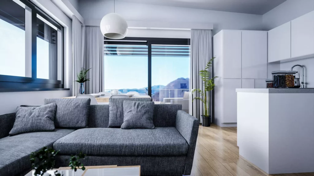 deutinger-projektentwicklung-baumanagement-generalunternehmen-immobilien-salzburg-projekt-mountainview-alpendorf-Wohnraum-Top-5 Modern eingerichtetes Wohnzimmer mit grauem Sofa, Essbereich, offener Küche und Bergblick durch große Fenster in Salzburg