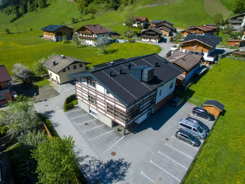 deutinger-projektentwicklung-baumanagement-generalunternehmen-immobilien-salzburg-wohnhaus-rohrmoser-01 Modernes Wohnhaus mit Parkplätzen in grüner ländlicher Umgebung in Rohrmoser bei Salzburg, Bauprojektmanagement sichtbar