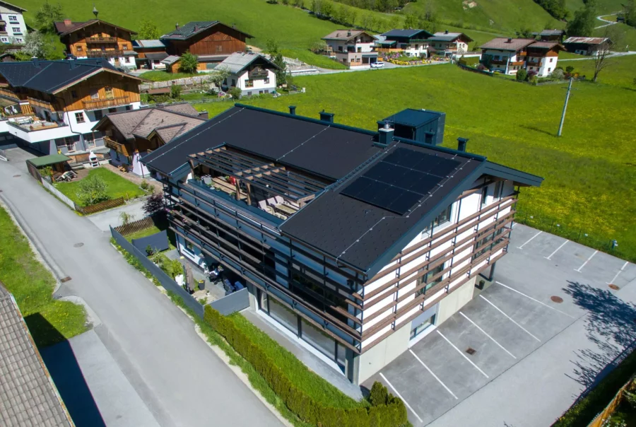 Modernes Wohnhaus mit Solarpanelen auf dem Dach in ländlicher Umgebung mit grünen Wiesen und weiteren Häusern in Rohrmoser