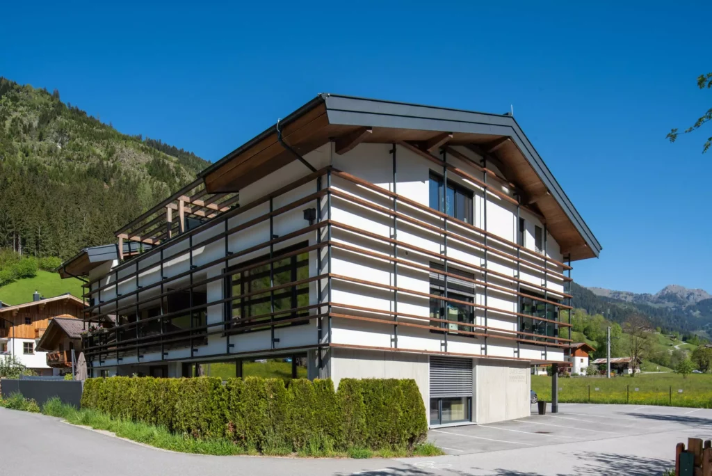 deutinger-projektentwicklung-baumanagement-generalunternehmen-immobilien-salzburg-wohnhaus-rohrmoser-03 Modernes Wohnhaus mit Holzverkleidung und großen Fenstern in ländlicher Berglandschaft bei Rohrmoser, Salzburg
