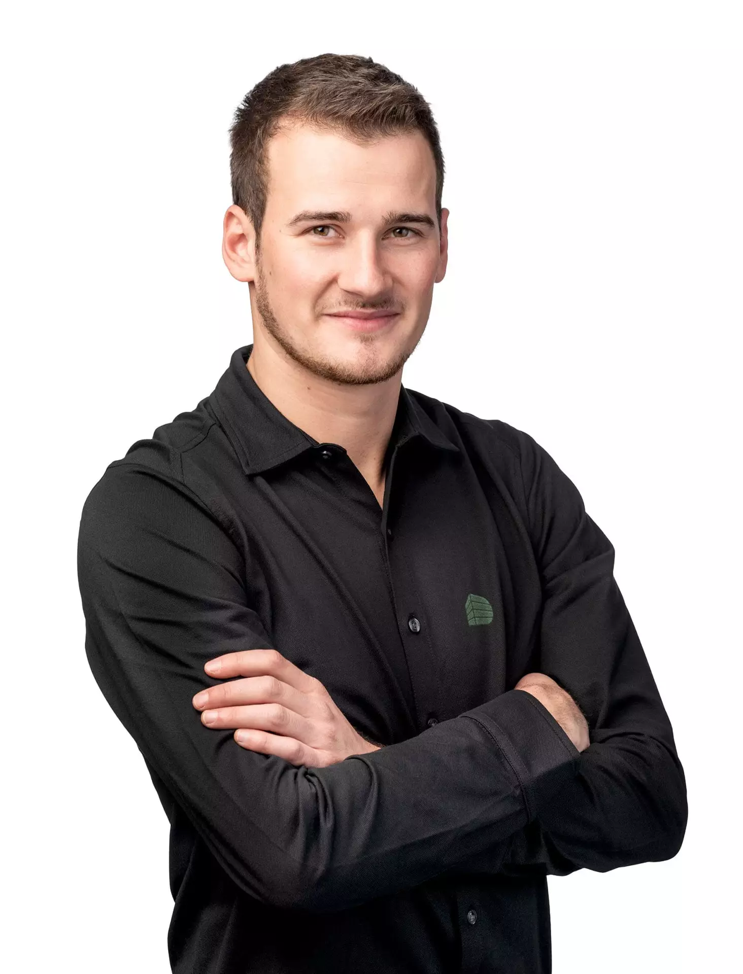 Porträt eines jungen Mannes mit schwarzem Hemd und verschränkten Armen vor weißem Hintergrund, Deutinger Team Hubert Aichhorn